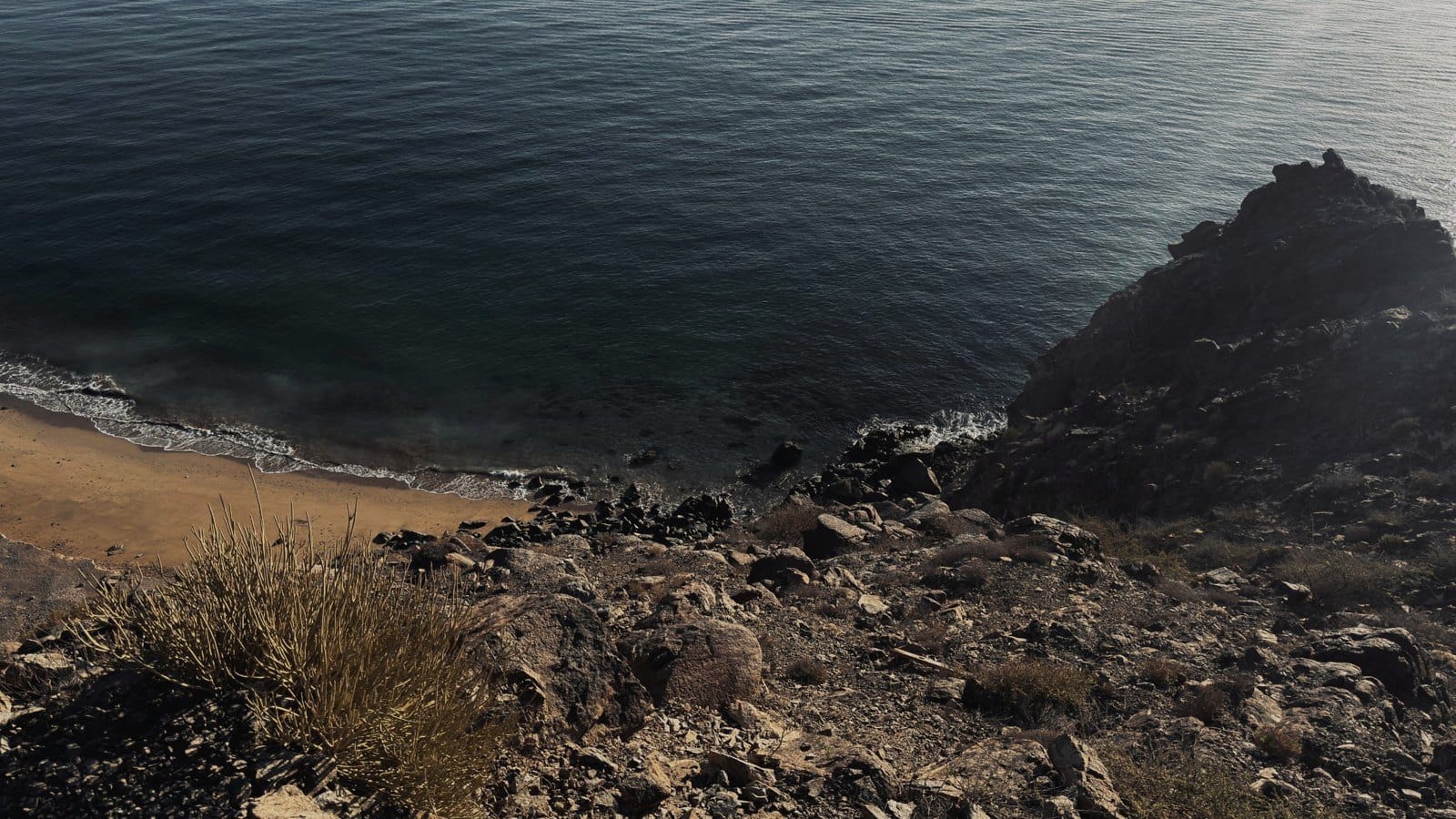 Looking down a rocky slope to a cove and the sea