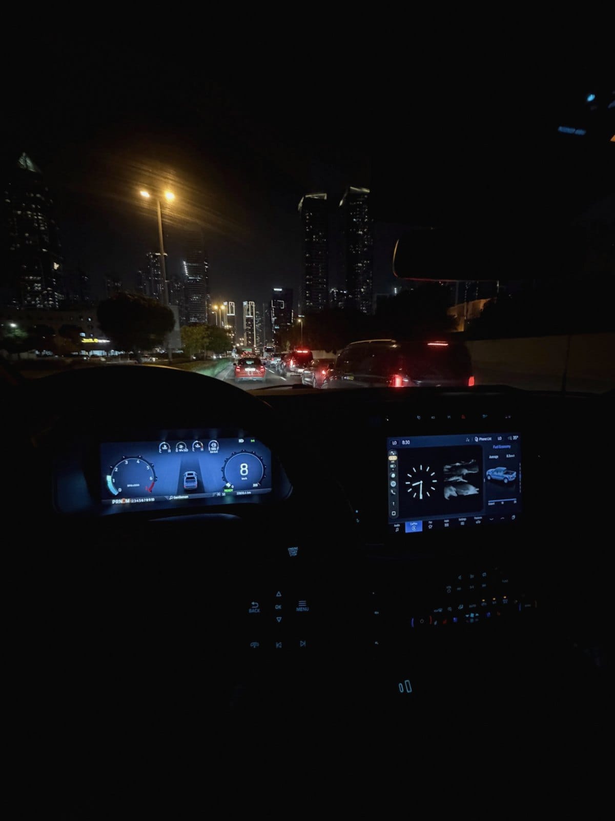Driving through Dubai at night, towers ahead and the dashboard glowing