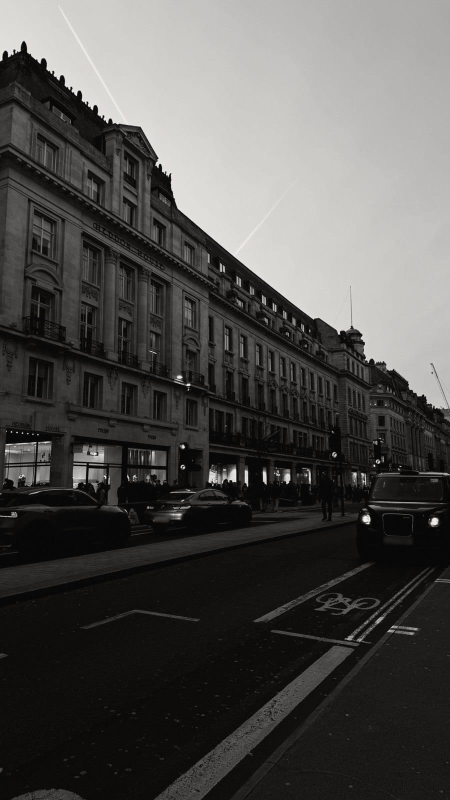 Black-and-white London street with stone buildings and a black cab